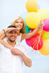 couple with colorful balloons at seaside
