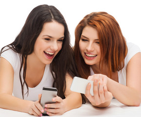 two smiling teenagers with smartphones