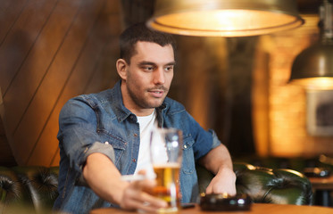 man drinking beer and smoking cigarette at bar