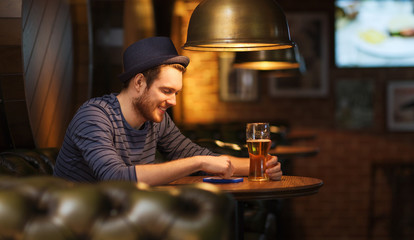 man with smartphone and beer texting at bar