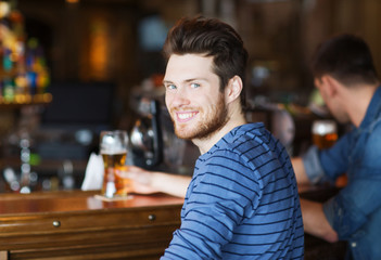 happy young man drinking beer at bar or pub