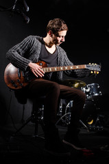 Man playing guitar in dark room
