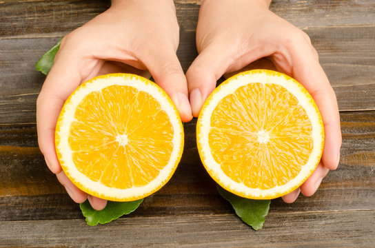 Slices of Navel orange fruit are holding by hand on wooden background,healthy food