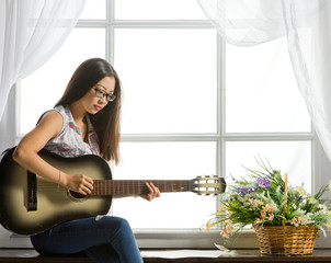 Young student girl playing music on guitar