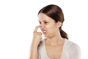 young woman scratching her nose on a white background