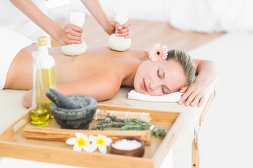 Obraz na płótnie Canvas Beautiful blonde enjoying a herbal compress massage
