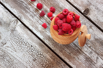 Raspberries in pot on wooden background