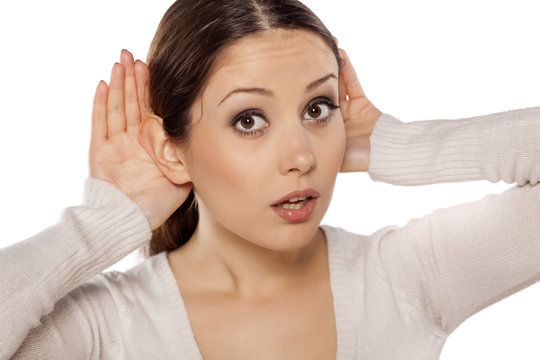 young woman carefully listening  with her hands behind the ears