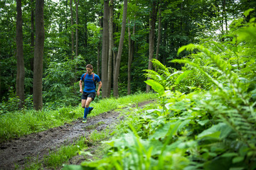 middle age trail runner training in the woods on the muddy track
