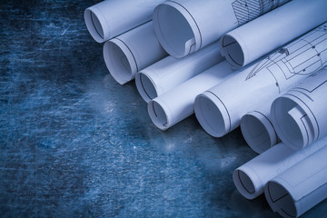 Rolled engineering drawings on scratched vintage metallic backgr