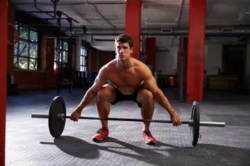 Fototapeta na wymiar Bare Chested Man In Gym Preparing To Lift Weights