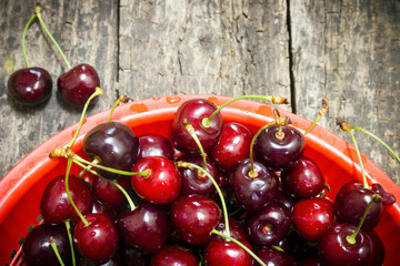 red bucket scoured rural cherries on a wooden table