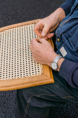 Ein Stuhl wird neu mit Rattan bespannt