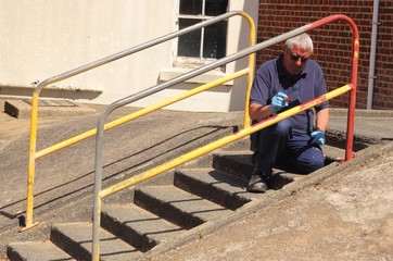 Obraz na płótnie Canvas A painter painting handrails along a walkway with concrete steps