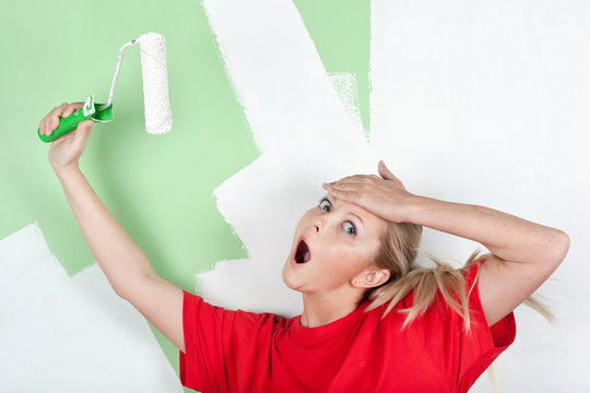 Shocked woman with paint roller in hand