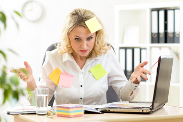 Funny overworked businesswoman working in office and looking at stickers reminder notes - obrazy, fototapety, plakaty