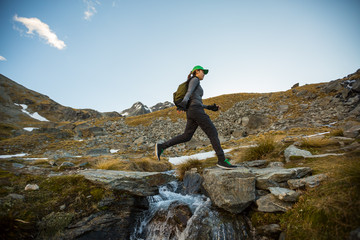 Female hiker leaping across a stream