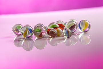 biglie in vetro su superficie riflettente rosa