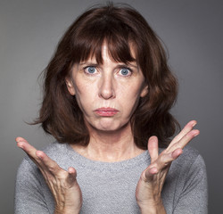 closeup portrait of frustrated 50's woman losing faith, pouting with palm hands opened for...