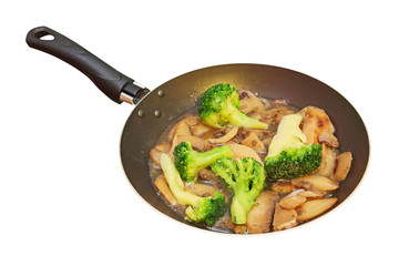 Roasted mushrooms and broccoli in frying pan.Isolated.