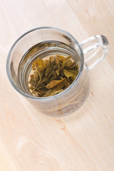 Green tea in glass cup with leafs on  board