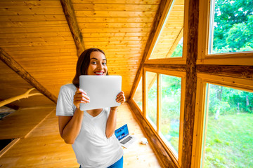 Woman with digital tablet in wooden house