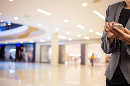 Women in shopping mall using mobile phone.