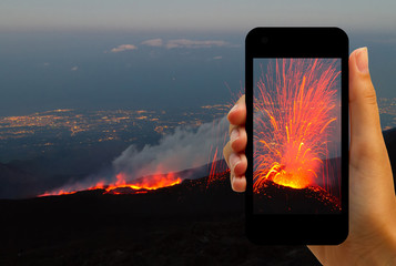 Tourist photographing the volcano eruption on smartphones  