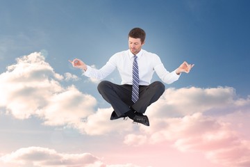 Composite image of businessman in suit sitting in lotus pose