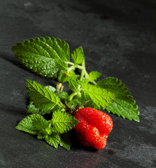 Fresh strawberries with mint leaves on a dark gray background, s