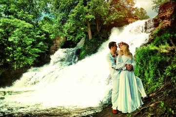 Fototapeta premium Young beautiful couple in traditional dress near waterfall