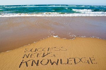 Success needs knowledge. Creative motivation concept written in the sand at the beach.