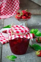 Confiture with strawberries and basil on a wooden background