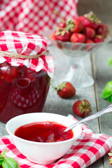 Confiture with strawberries and basil on a wooden background