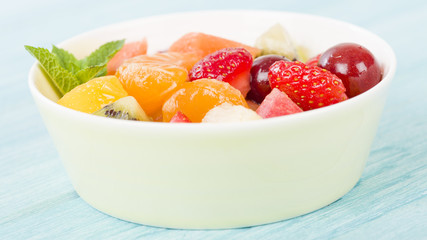 Fruit Salad - Bowl of fresh fruit salad on a blue background.