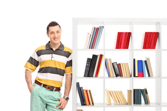 Casual young guy leaning against a bookshelf