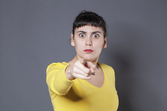 stunned young brunette woman staring at someone with index finger forward recognizing and accusing someone with fear in eyes