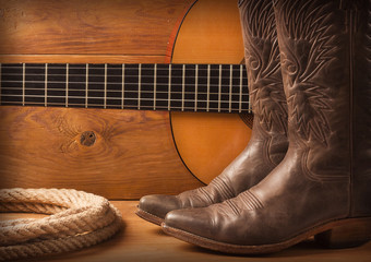 American Country music with guitar and cowboy shoes on wood text