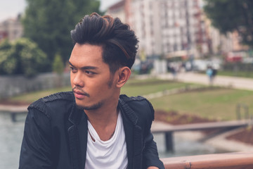 Handsome Asian model posing by an artificial basin