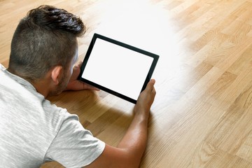 Mann betrachtet Tablet im Liegen