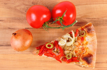 Slice of vegetarian pizza, tomatoes and onion on wooden surface