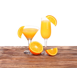 Glass of freshly pressed orange juice with sliced orange half on wooden table