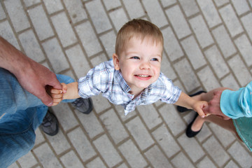 Naklejka premium Happy little boy holding fingers of father and mother