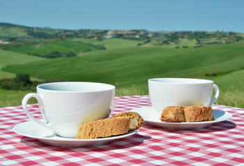 Coffee and cantuccini on the table against Tuscan landscape. Ita