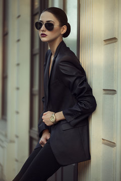 Fototapeta Female beauty concept. Portrait of fashionable young girl in classic clothes (suit) and sunglasses posing on the street. Perfect hair & skin. Vogue style. outdoor shot