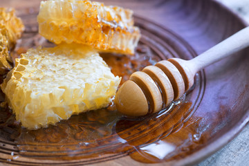 Honey in jar with honey dipper on vintage wooden background