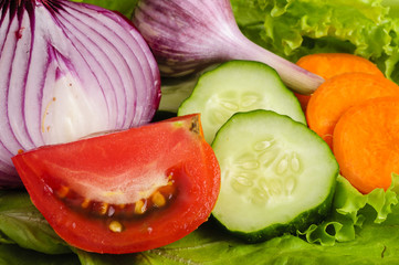 Tomato, onion, garlic, cucumber and carrots on lettuce leaves