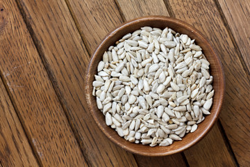Shelled sunflower seeds in wood bowl isolated from above on rust
