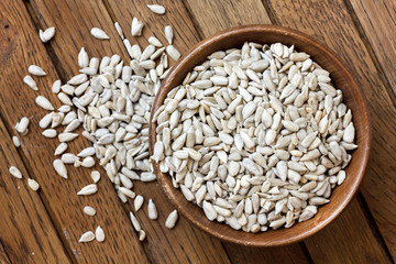 Shelled sunflower seeds in wood bowl isolated from above on rust