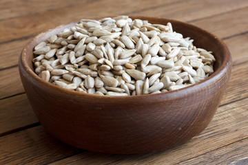 Shelled sunflower seeds in wood bowl on rustic table.